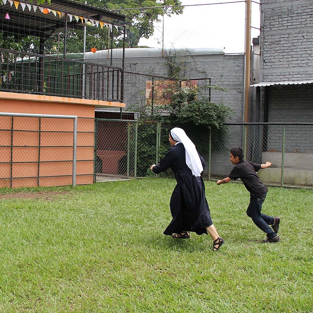Eine Schwester spielt in El Salvador Fußball mit einem Jungen.