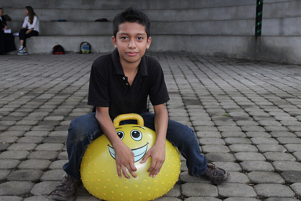 Ein Junge aus El Salvador auf einem Hüpfball.
