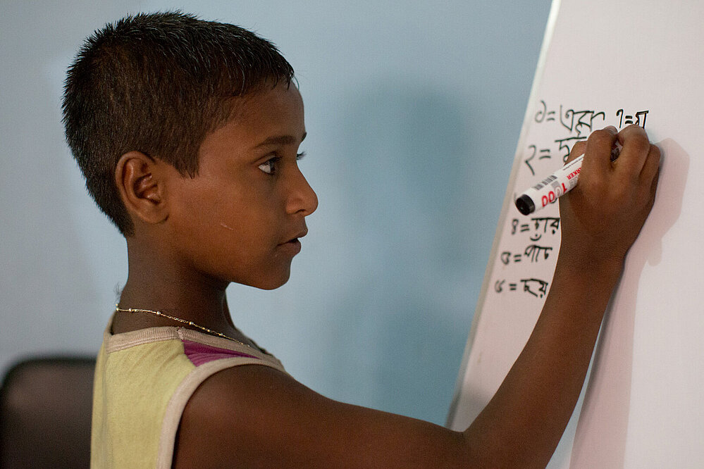 © Katrin Harms / Kindermissionswerk Ein Junge aus Bangladesch schreibt etwas auf ein Whiteboard